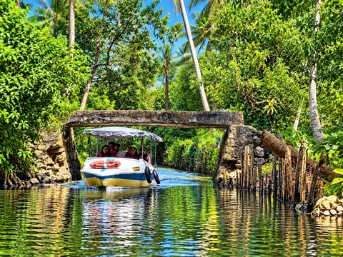 Boat under the old stone bridge in a Poovar canal – Poovar Boating
